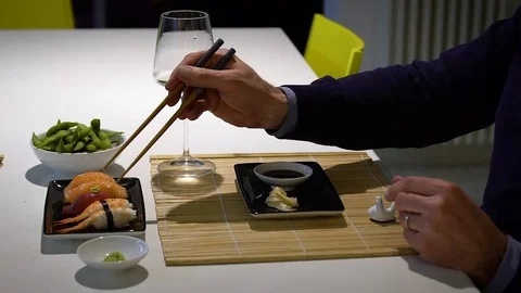 Slow motion video of  man with a beard eating sushi and drinking white .. Stock Footage 71564219