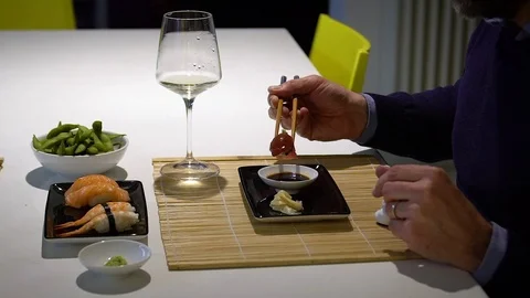 Slow motion video of  man with a beard eating sushi and drinking white .. Stock Footage 71564616