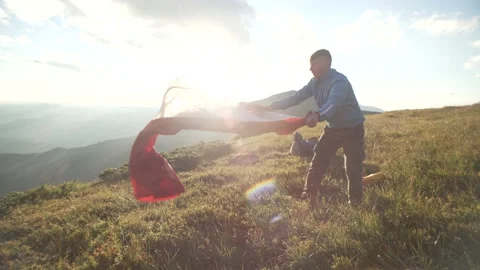 Slow motion video of a man pitching a tent in a mountain landscape. Stock Footage 218439749
