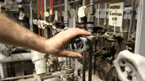 A slow motion video of a man's hand openin and cloding a valve on a plant Video stock 201414216
