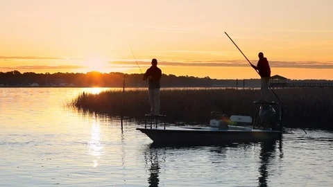 Slow motion video of men fly fishing with the sun coming up behind their boat. Stock Footage 120994551