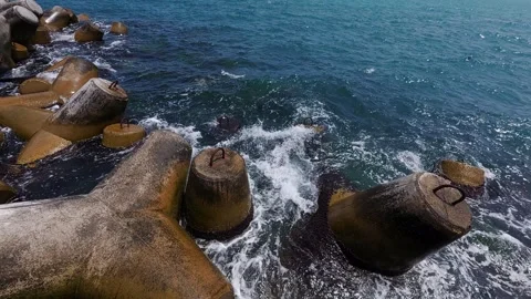 Slow motion video of ocean waves crashing against mossy concrete tetrapods on a Video stock 311155338