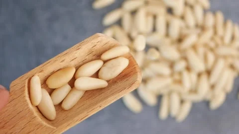 Slow motion video of pine nuts falling from wooden scoop onto gray backgrou.. Stock Footage 333153459
