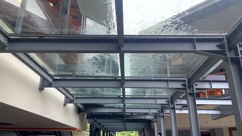 Slow motion video of raindrops trickling down a modern glass canopy. Stock Footage 320504455