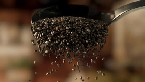 Slow motion video of raw chia seeds falling from a silver spoon Stock-Footage 332870726