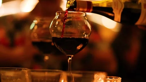 Slow motion video of red wine pouring from bottle into glass during evening.. Stock Footage 332708029