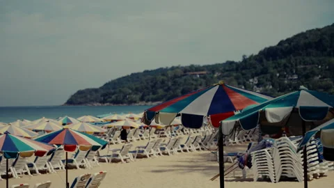 Slow motion video showcasing vibrant beach umbrellas and empty sunbeds on a Stock Footage 308568126