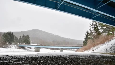 Slow motion video snow under bridge, river park path Stock Footage 262379351