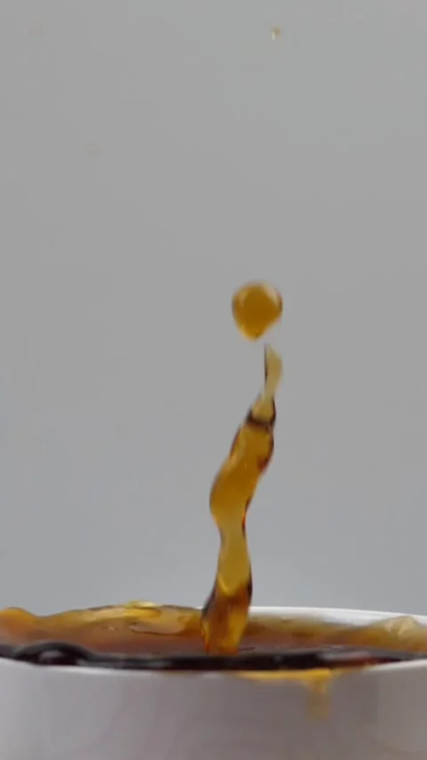 Slow motion video of three brown sugar cubes falling into a cup of black tea Stock Footage 307811500