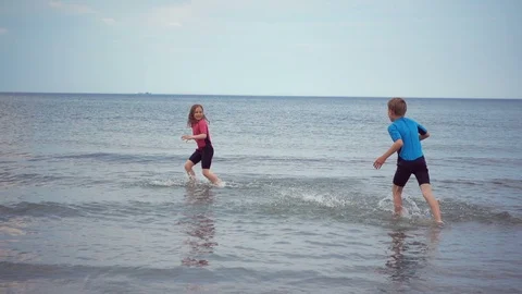 Slow-motion video of two happy children in neoprene swimsuits running on the  Stock Footage 111658108