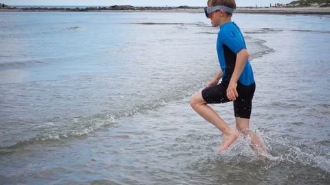 Slow-motion video of two happy children in neoprene swimsuits running on the  Stock Footage 111659666