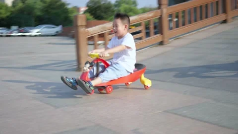 Slow motion video of two little Chinese boys playing with scooters on a square i Stock Footage 221457950