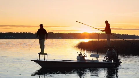 Slow motion video of two men fly fishing from a boat at sunrise. Video stock 121000512