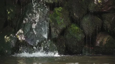 Slow motion video of waterfall running through mossy stones Stock Footage 156973329