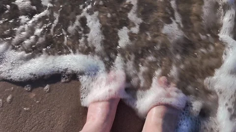 Slow motion video of waves breaking against human bare feet sanding on gold.. Stock Footage 319408992
