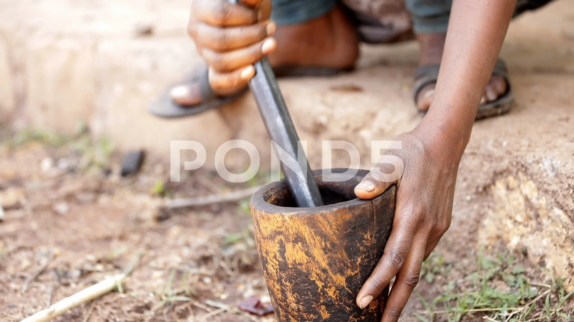 slow motion video of woman grinding coffee in mortar and pestle in Africa