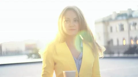 Slow motion video. Young beautiful girl in a yellow jacket near office walking Stock Footage 65403588