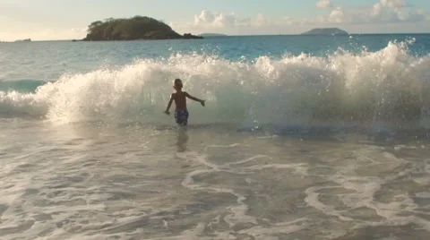 Slow motion video of young boy running into a wave in the Caribbean  Stock Footage 67599693