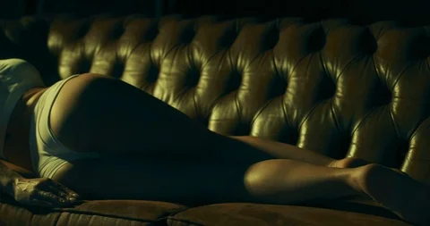 Slow motion video of a young charming woman seductively lying on a sofa in Stock Footage 123212988