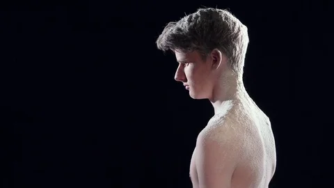 Slow motion video of a young man sprinkled dust and blowing by the strong wind Video stock 75101829