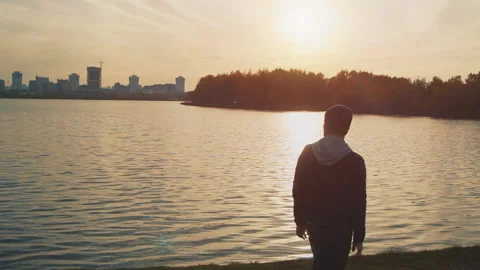 Slow motion video of a young man jumping mid-air by a lake Stock Footage 99389386