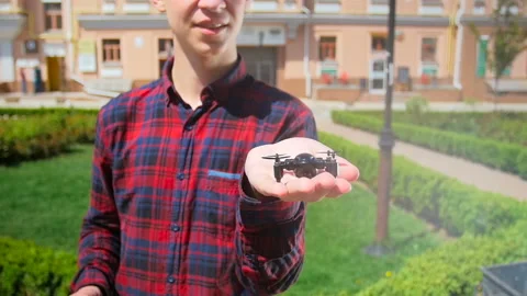 Slow motion video of young man showing tiny drone for shooting video or Stock Footage 107531361
