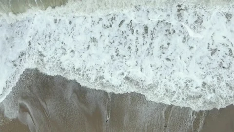 Slow-motion view from above waves roll onto the sandy shore Stock Footage 132180794