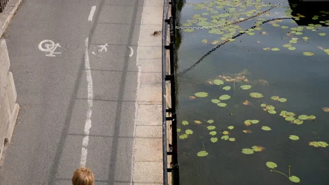 Slow motion view of bike path with cyclists and electric scooter next to water Stock-Footage 131939003