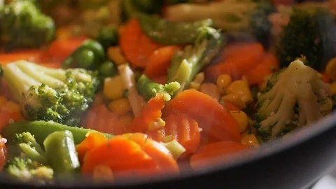 Slow-motion view of the chef stirring fresh vegetables with a spatula cooking in Stock Footage 107437283