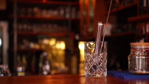 Slow motion view on clear transparent whiskey glass on bar counter in modern Vidéo 103804915