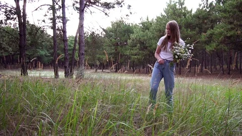 Slow motion view on dreamy young girl collecting field flowers to compose Stock Footage 102338359