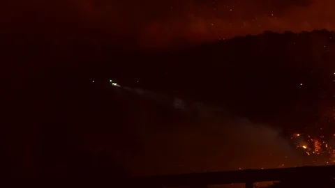 Slow motion view of a fire control helicopter, extinguishing wild fire, at Vidéo 121810070