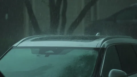 Slow motion view of Heavy rain falling on parked car in suburban neighborhood Vidéo 345478440