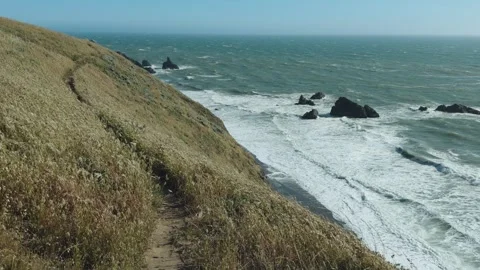 Slow motion view of hiking trail carving along a steep windy coastal hillside Stock Footage 336524512