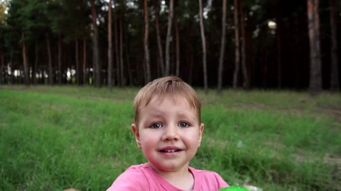 Slow motion view on little boy reaching out to touch camera in wild nature green Stock Footage 104148711