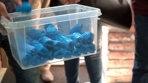 Slow motion view of a man giving everyone shoe covers. Stock Footage 119768069