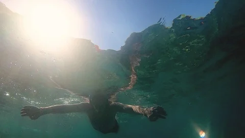 Slow Motion View: Man Jumps Into The Sea With Sunrays Illuminating Him 스톡 동영상 121310919