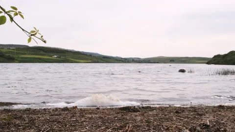 A slow motion view overlooking a Scottish Loch with small waves and foam Stock Footage 138412618