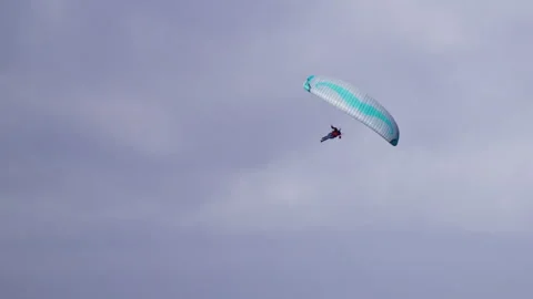 Slow motion view of paraglider maneuvering wing downwards over Dutch coastline Vidéo 328389656