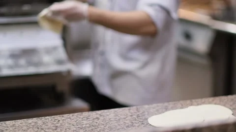 Slow-motion view of a person throwing pressed pita bread dough on a table Stock Footage 221900966
