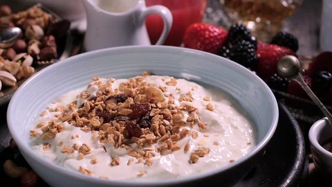 Slow motion view: Pouring cereals over a bowl of yogurt Stock Footage 73528364