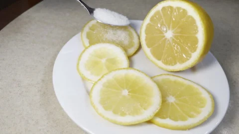 SLow motion view pouring sugar on sliced lemon lying on white plate on table Stock Footage 262530583
