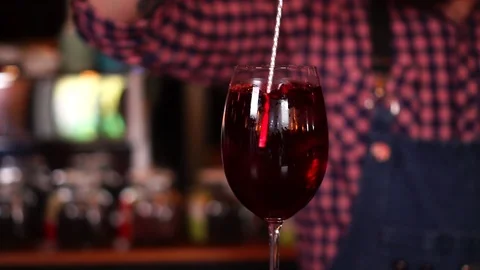 Slow motion view on process of drink mixing alcohol cocktail in red wine glass Stock Footage 104373629