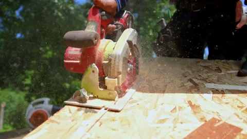 Slow motion view of Roofer cutting a wooden board with a circular saw during Stock Footage 346790472