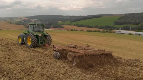 Slow motion view of tractor plowing a field a from drone Stock Footage 95336332