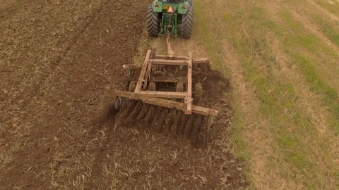 Slow motion view of tractor plowing a field a from drone Stock Footage 95336439