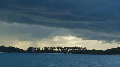 Slow Motion View of Tropical Palm Trees Beneath Dark Storm Clouds Across a Calm Stock Footage 338188179