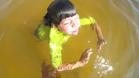 Slow motion view of young boy swimming in murky thermal water pool Stock Footage 344669656