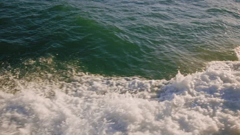 Slow motion of wake and surf created by boat passing through water at sunset Stock Footage 242832620