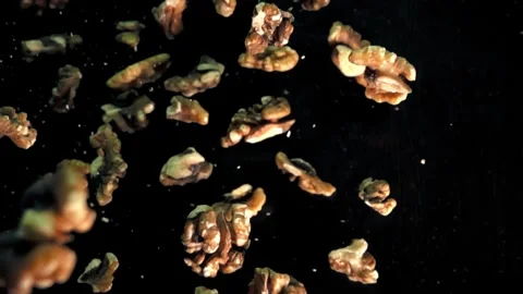 Slow Motion Walnut Pieces Falling on a Dark Background in a Studio Setting Stock Footage 272190395